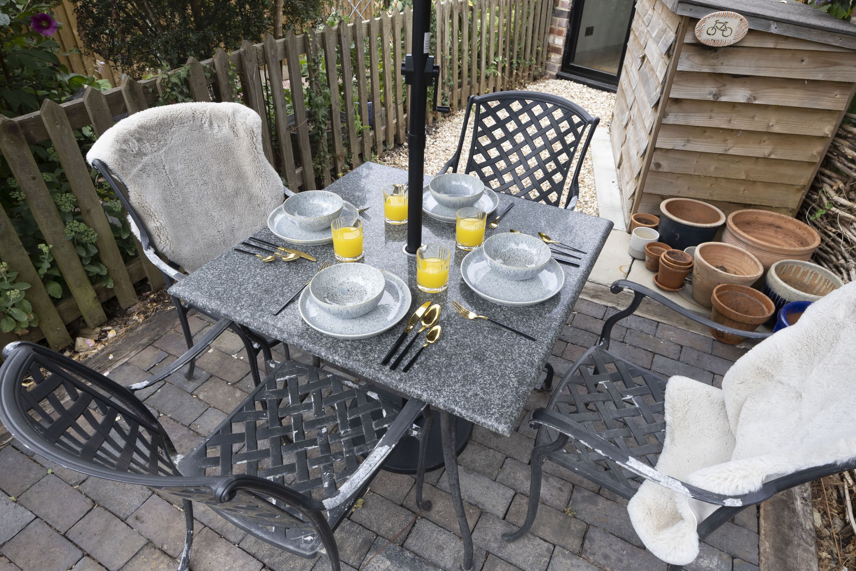 An outdoor dining area with a table set for four, surrounded by chairs.