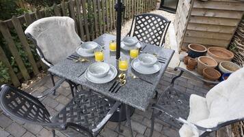 An outdoor dining area with a table set for four, surrounded by chairs.