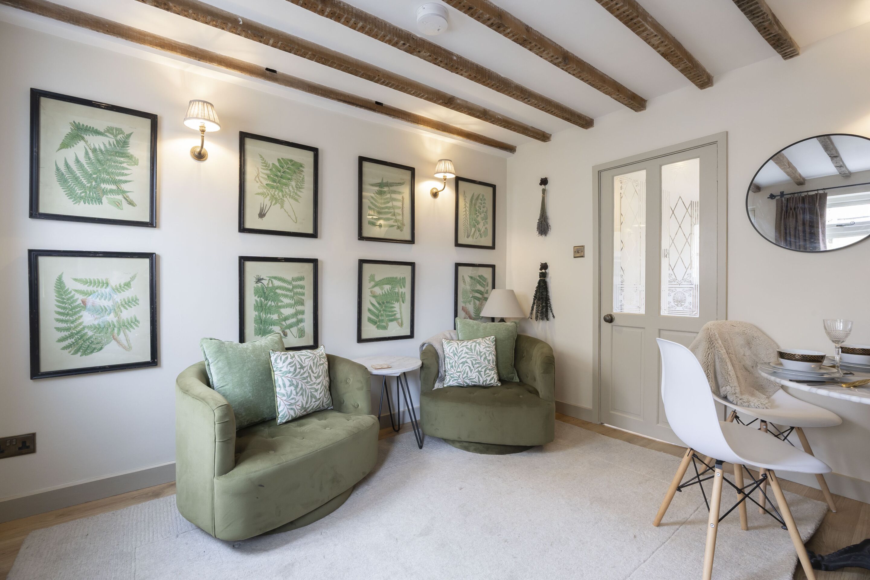 A room with two green armchairs, a small table, and a dining area with a white chair and table.