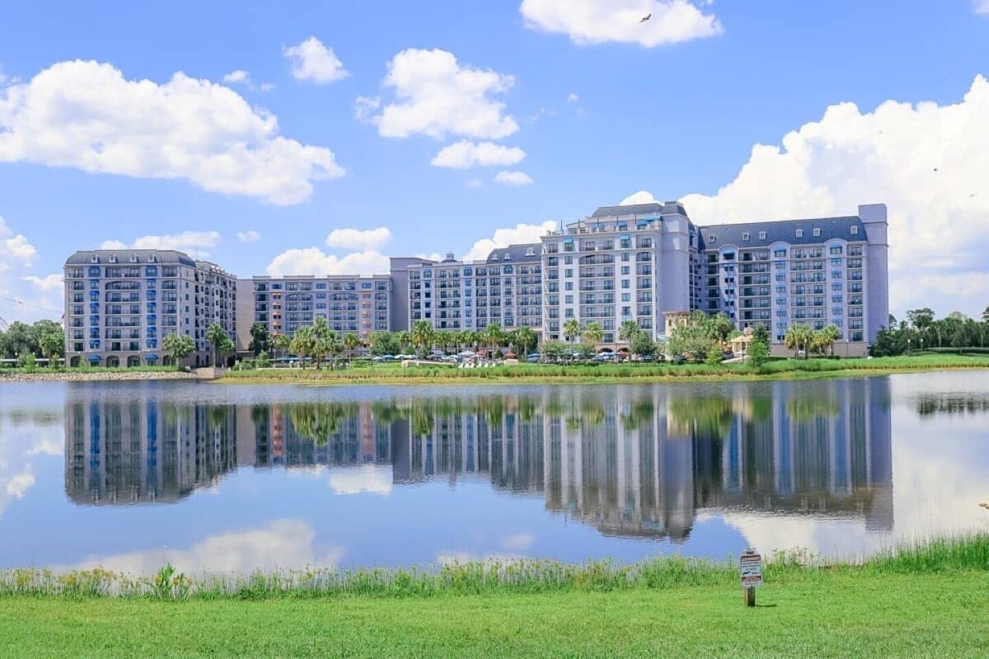 Un vaste complexe hôtelier comprenant plusieurs immeubles de grande hauteur, un lac paisible en contrebas et un ciel bleu dégagé.
