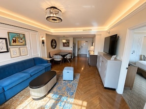 A modern living room with a blue sofa, a coffee table, and a dining area with a table and chairs. - Orlando | Family Riviera Retreat | Pool + Resort | 2BR (Lake Buena Vista)