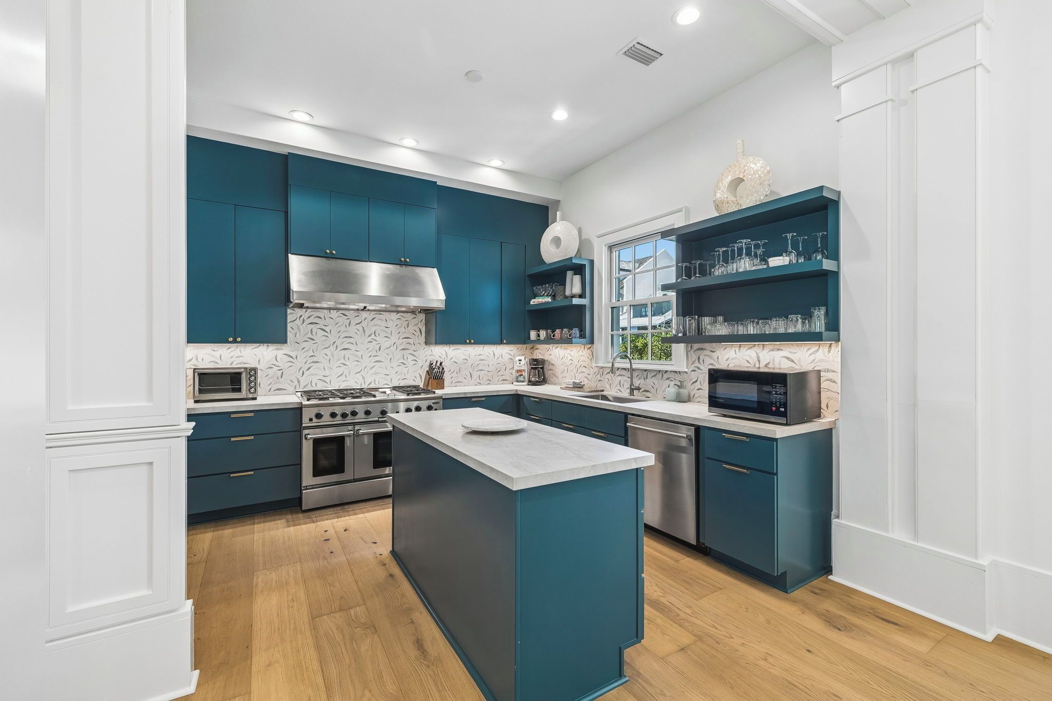Una cocina moderna con armarios color turquesa, electrodomésticos de acero inoxidable y una isla central.
