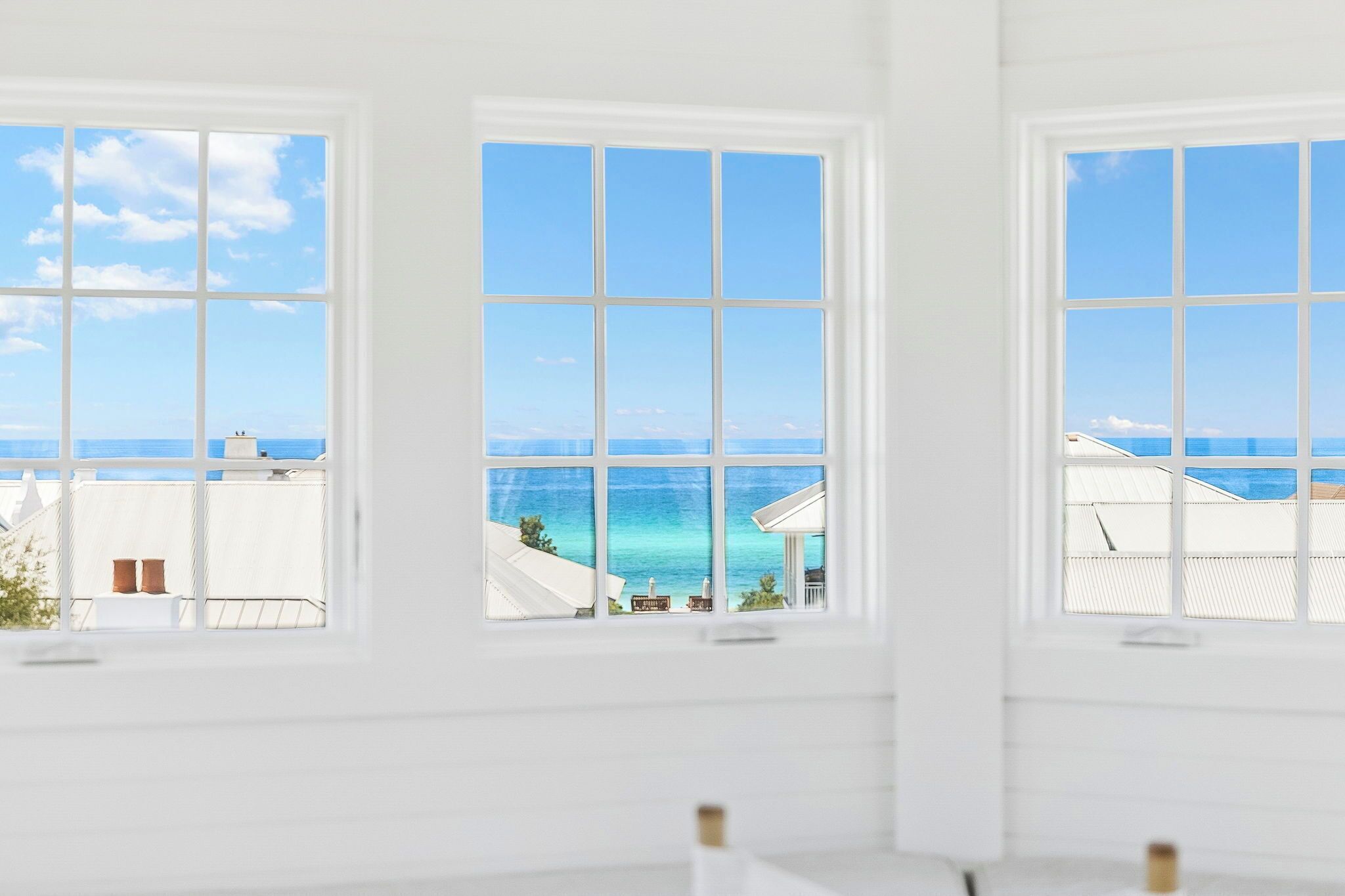 A room with large windows offering a view of the sea and buildings.
