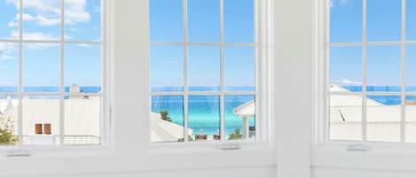Ein Zimmer mit großen Fenstern und Blick auf das Meer und die Stadt.