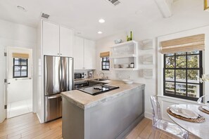 A modern kitchen with a stainless steel refrigerator, a built-in oven, and a central island with a stove. - Carriage House with Gulf Views (Rosemary Beach)