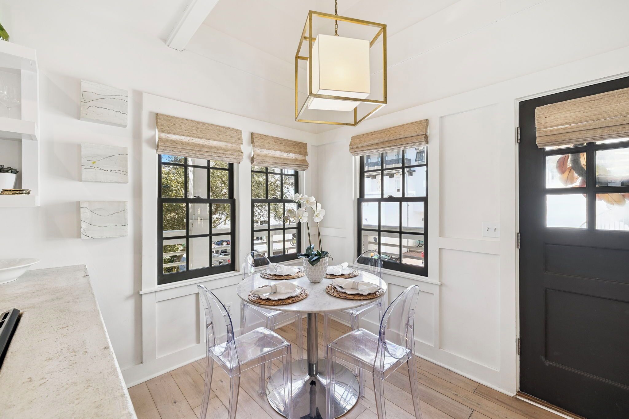 Un coin repas avec une table ronde, des chaises transparentes et une porte noire.