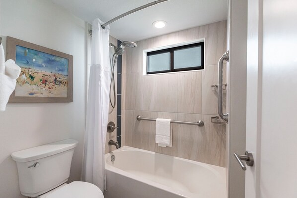 A bathroom with a toilet, a shower with a glass door, and a bathtub.