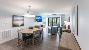 A modern living room with a dining area, large windows, and a view of the outdoors.