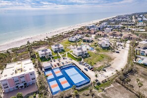 An aerial view of a coastal resort with multiple buildings, a beach, and a tennis court. - Sanibel Beach Club  (Sanibel)