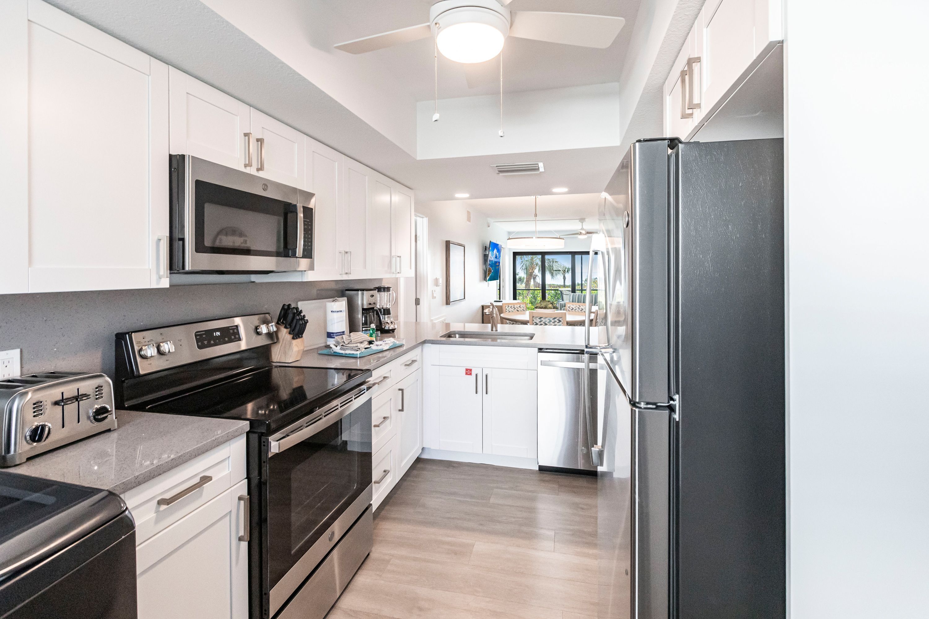 A modern kitchen with stainless steel appliances, white cabinetry, and a view to the outside.