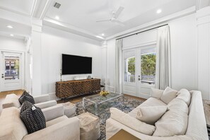 A modern living room with a flat-screen TV, a stone-patterned coffee table, and a beige sofa. - Porches | Gulf Views | Carriage House (Rosemary Beach)