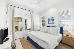 A bedroom with a bed, a TV, a desk, and a window. - Porches | Gulf Views | Carriage House (Rosemary Beach)