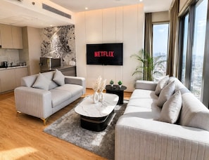 Ein modernes Wohnzimmer mit Flachbildfernseher, zwei Sofas, einem Couchtisch und Blick auf die Stadt.