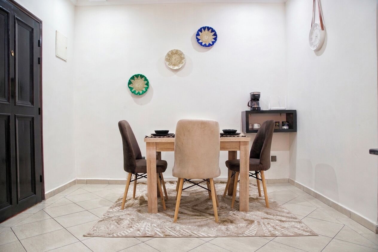 Een eetgedeelte met een tafel, vier stoelen en decoratieve borden aan de muur.