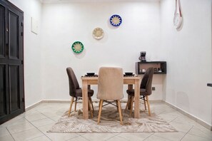 Een eetgedeelte met een tafel, vier stoelen en decoratieve borden aan de muur.