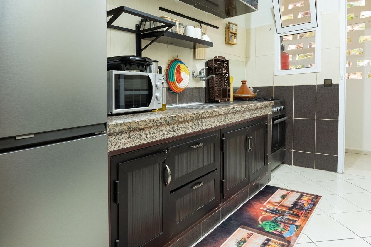 Een keuken met een magnetron, fornuis, kasten en een kleurrijk vloerkleed.
