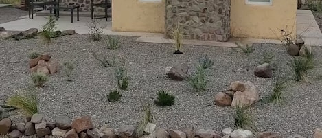 A modern house with a stone facade, two windows, and a gravel driveway.