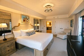 Habitación de hotel con una cama grande, mesitas de noche, un escritorio, una silla, televisión y baño visible a través de una puerta abierta.
