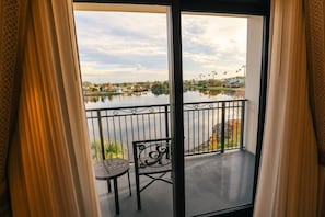 A balcony with a view of a lake, a chair, and a table. - Orlando • Grand Family Escape • Pool + Resort • 3BR Sleeps 12 (Lake Buena Vista)