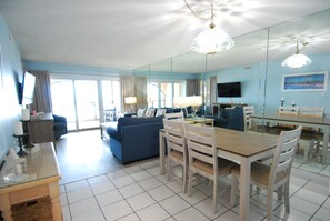 Een moderne woonkamer met een bank, eettafel, stoelen en een televisie.
