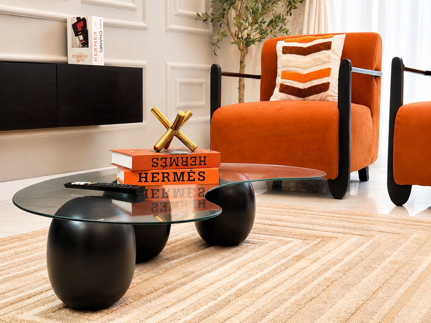A modern living room with a glass coffee table, a black sofa, and a bookshelf.