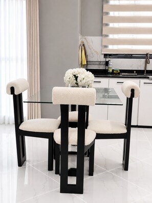 Un comedor moderno con una mesa de vidrio y cuatro sillas con asientos y respaldos acolchados.