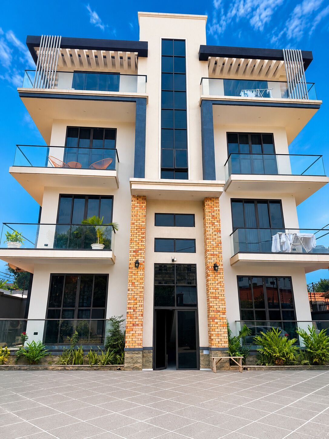 Un immeuble moderne à plusieurs étages, doté d’une entrée centrale, de balcons à chaque étage et surplombant un ciel dégagé.