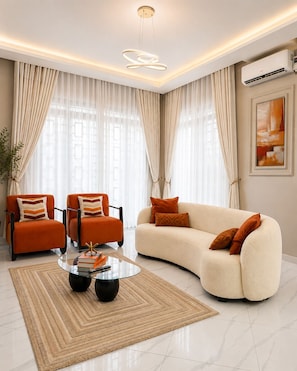 Una sala de estar moderna con un sofá, dos sillones, una mesa de centro y una mesa con cubierta de vidrio.