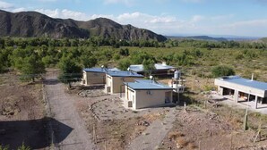 A rural property with multiple buildings, including a main house and several smaller structures, surrounded by a natural landscape with mountains in the background.