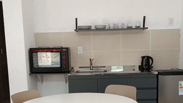 A compact kitchen with a microwave, kettle, and a small dining area with a table and chairs.