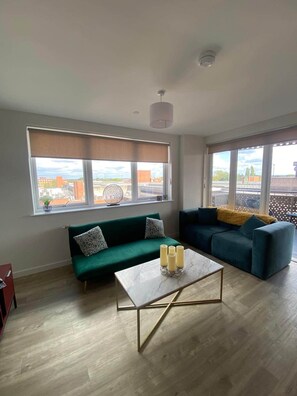 Ein modernes Wohnzimmer mit zwei Sofas, einem Couchtisch und großen Fenstern mit Blick auf die Stadt.