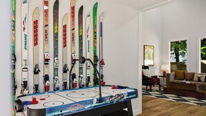 Una habitación con mesa de fútbol de mesa, un sofá y esquíes apoyados en la pared.