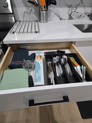 A kitchen drawer with utensils, a strainer, and a wax paper box. - Imperial Lodge:3BD Peaceful Getaway Suite+King Bed (Edmonton)