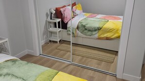 A bedroom with a bed, a bedside table, a mirror, and a wardrobe. - Imperial Lodge:3BD Peaceful Getaway Suite+King Bed (Edmonton)