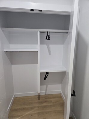 A walk-in closet with white walls and a wooden floor. - Imperial Lodge:3BD Peaceful Getaway Suite+King Bed (Edmonton)
