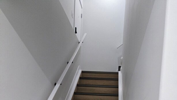 A staircase with wooden steps and white walls. - Imperial Lodge:3BD Peaceful Getaway Suite+King Bed (Edmonton)