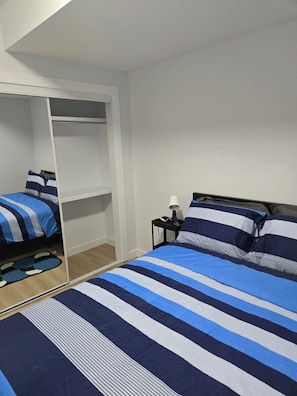 Ein Schlafzimmer mit zwei Betten, einem Kleiderschrank und einem Nachttisch mit Lampe.