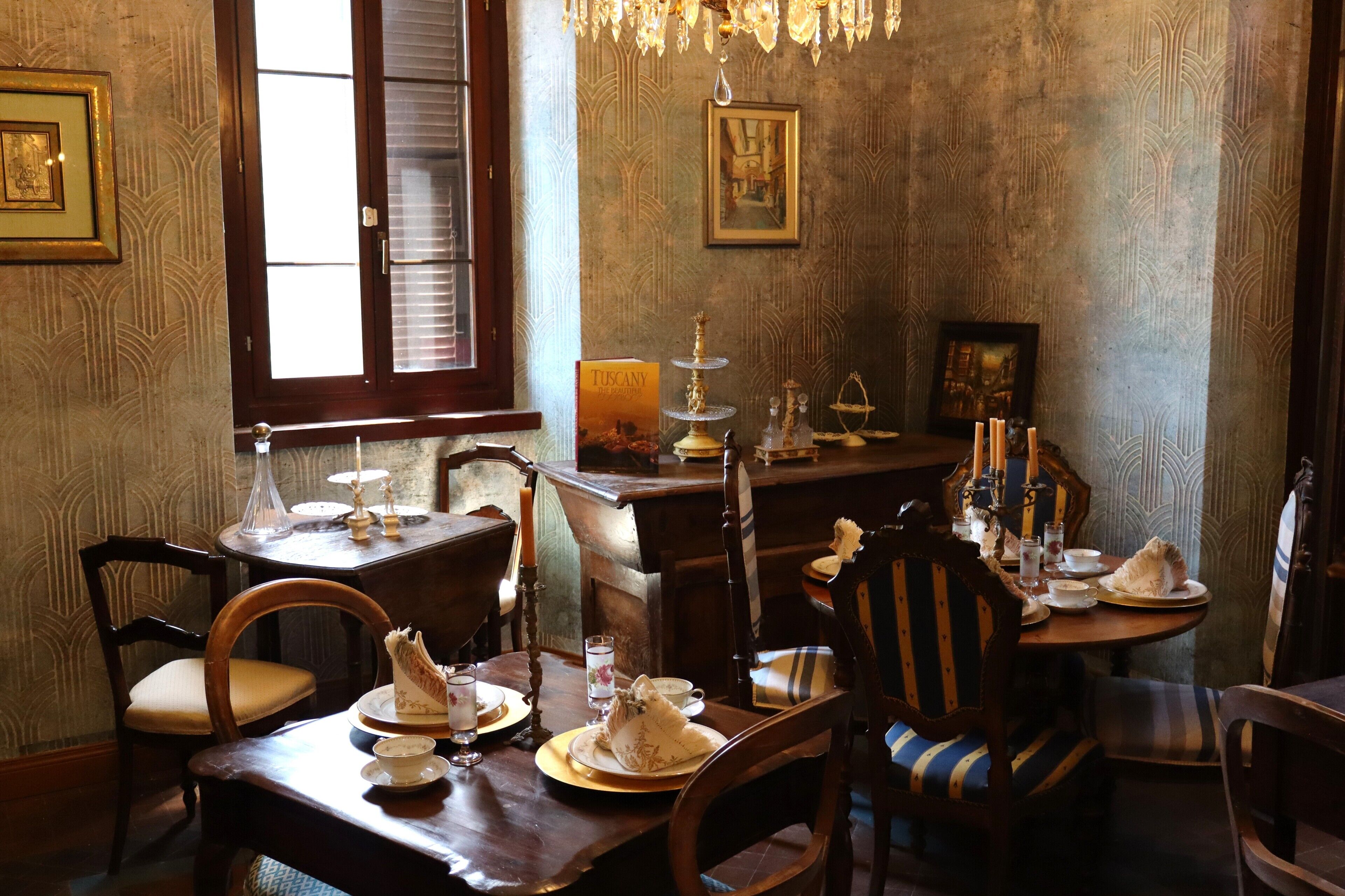 Une salle à manger meublée de meubles en bois, ornée d’un lustre et de tableaux encadrés aux murs.