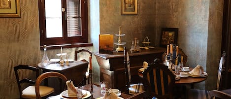 A dining room with wooden furniture, a chandelier, and framed artwork on the walls.