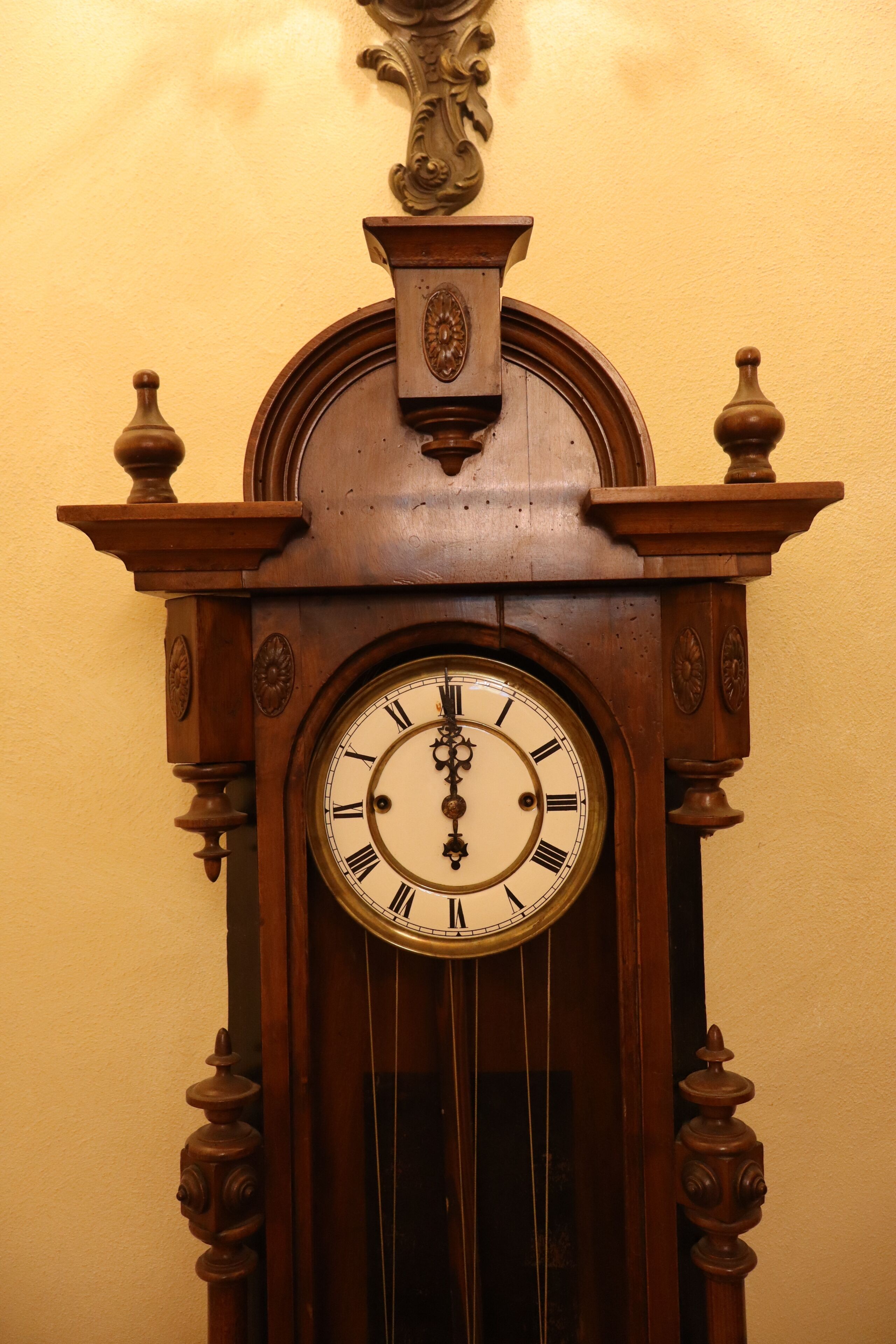 A wooden grandfather clock with Roman numerals and a pendulum.