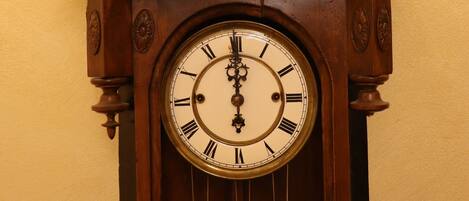 A wooden grandfather clock with Roman numerals and a pendulum.