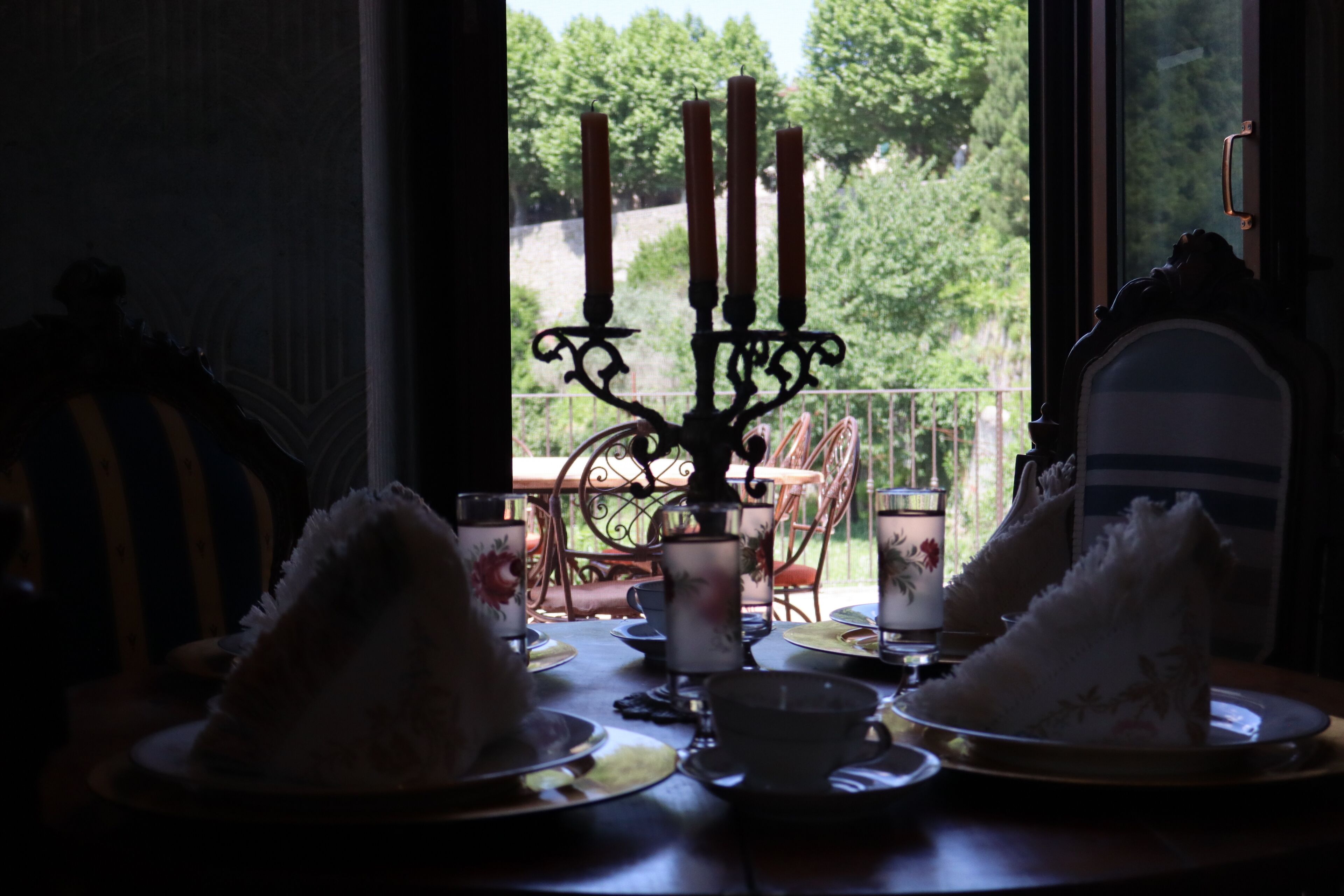 A dining table with plates, cups, and a candelabra.