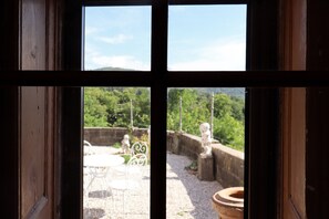 Una ventana con vista a un jardín que incluye una estatua y una fuente.