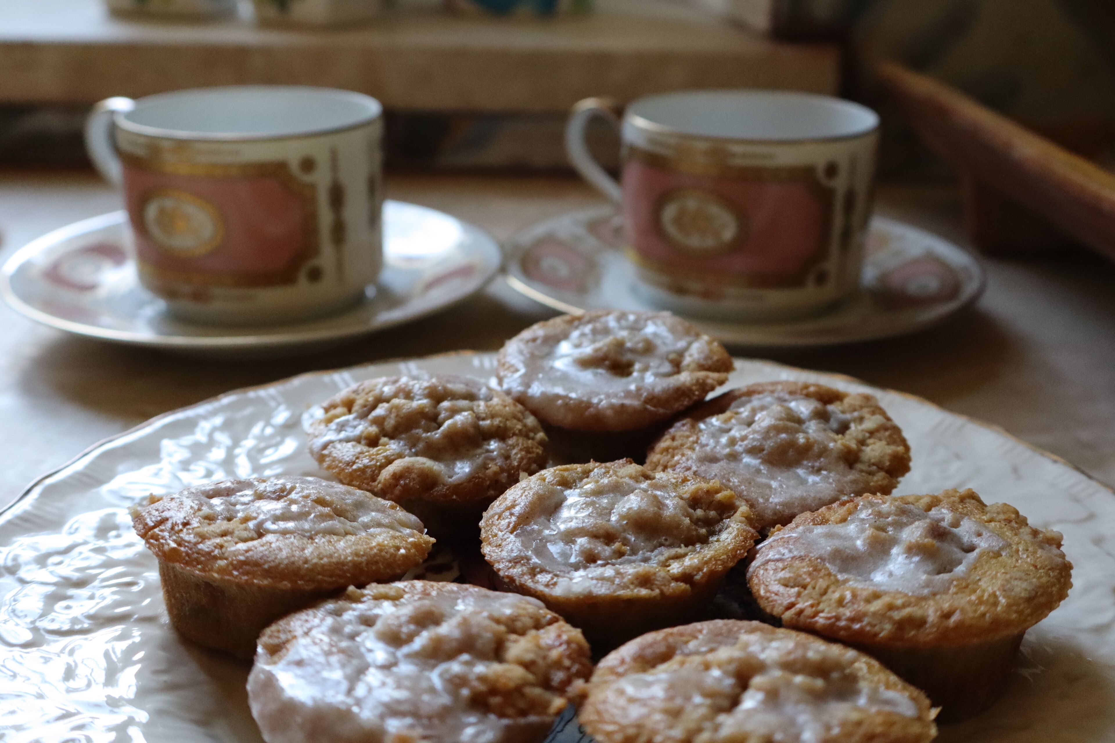 A plate of pastries on a table with two cups in the background.