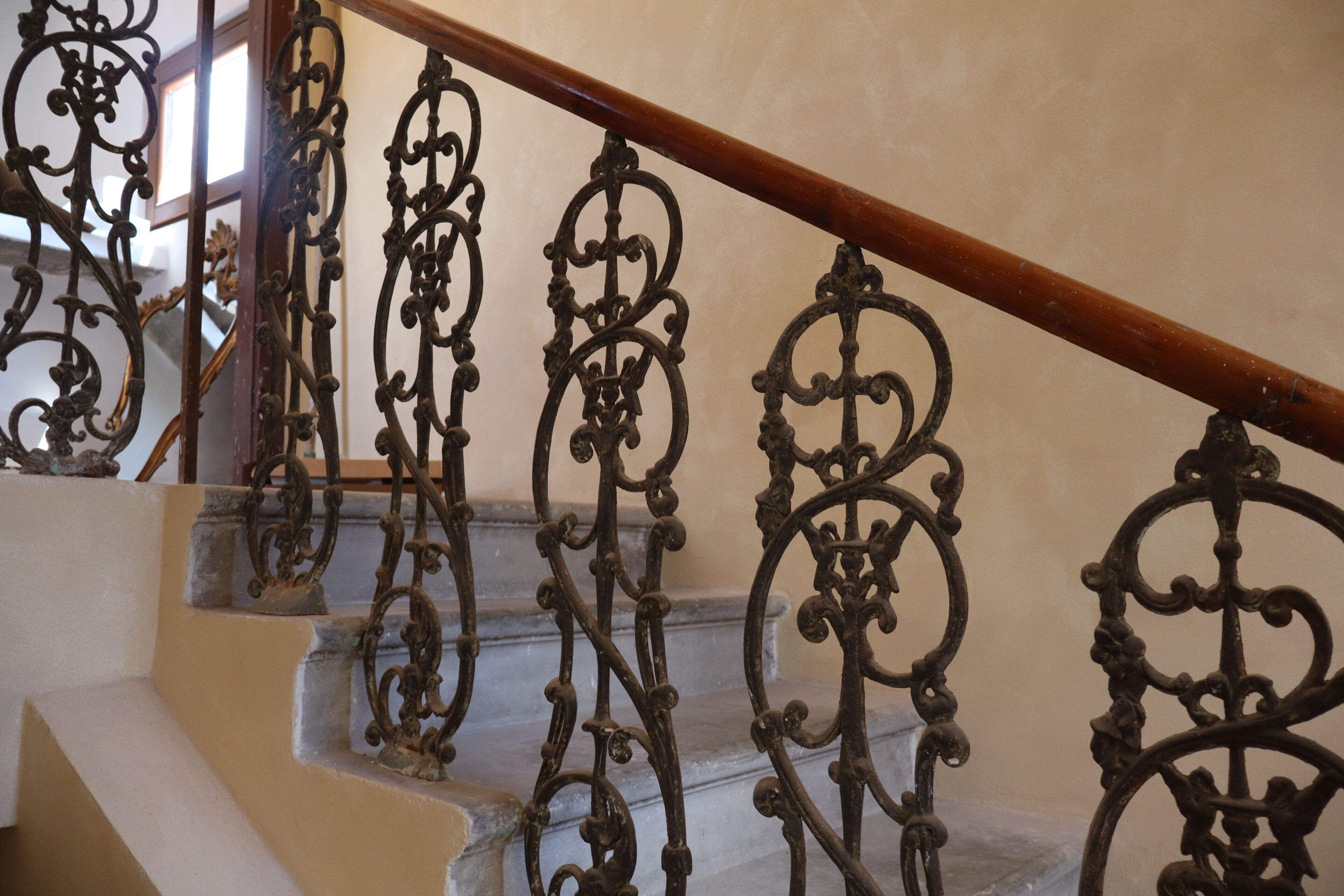 A staircase with ornate metal railings and a wooden handrail.