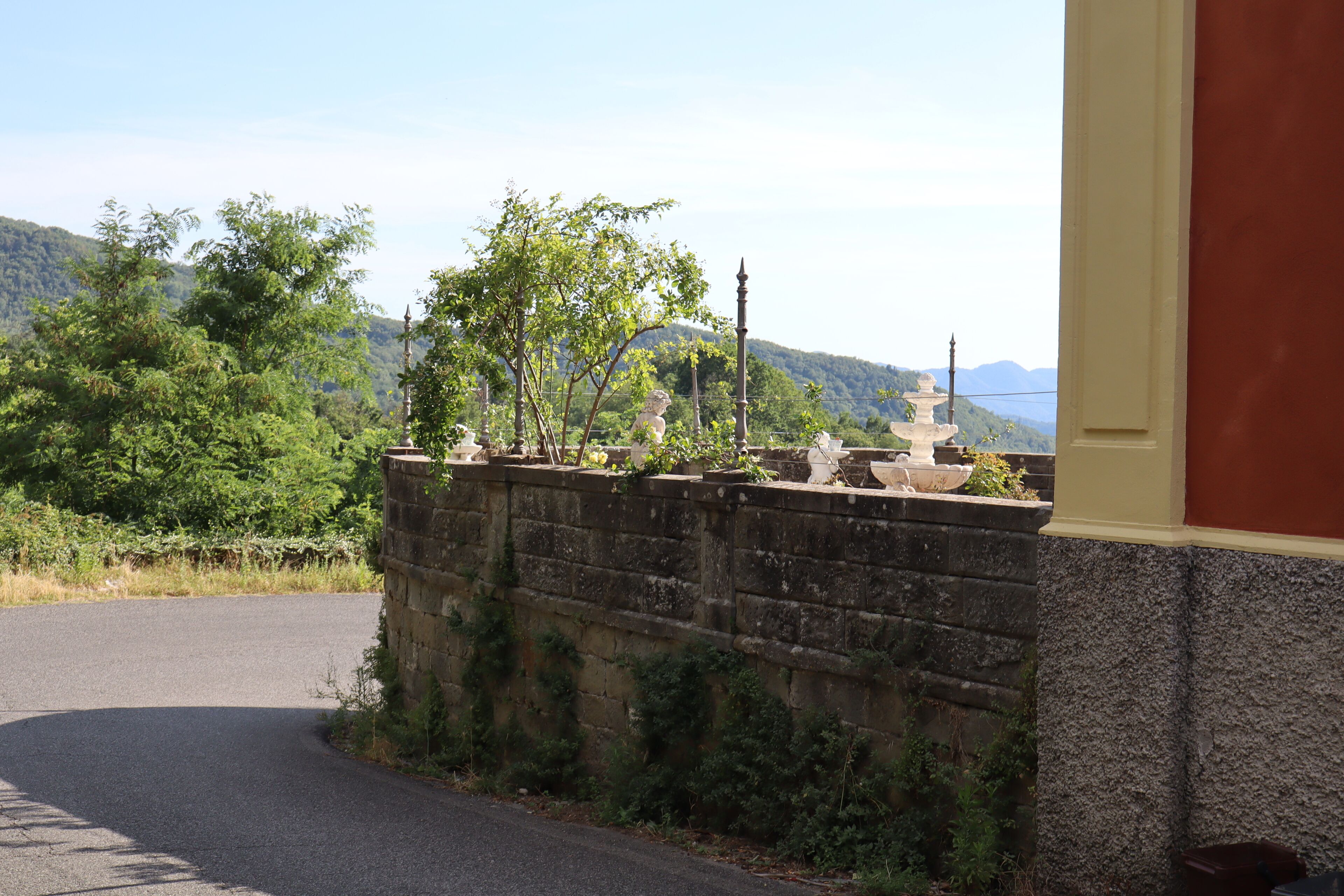 Une route asphaltée qui tourne vers la gauche, avec un mur de pierres sur la droite.