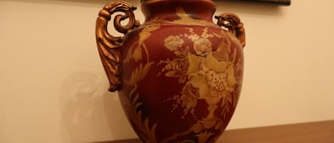 A red ceramic vase with floral patterns on a wooden surface.