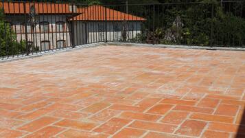 Un cortile con piastrelle in terracotta, una recinzione in metallo e un edificio con tetto in tegole.