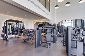 A modern gym with various exercise machines, mirrors, and a spacious layout. - Luxury 4-bedroom condo At 72 Park With Gym, Pool, Tiki bar and Beach Service (Miami Beach)