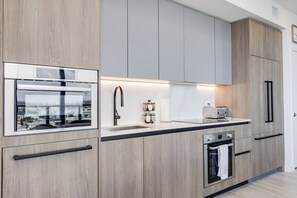 A modern kitchen with a built-in oven, a sink, and a window with a city view. - Luxury 4-bedroom condo At 72 Park With Gym, Pool, Tiki bar and Beach Service (Miami Beach)